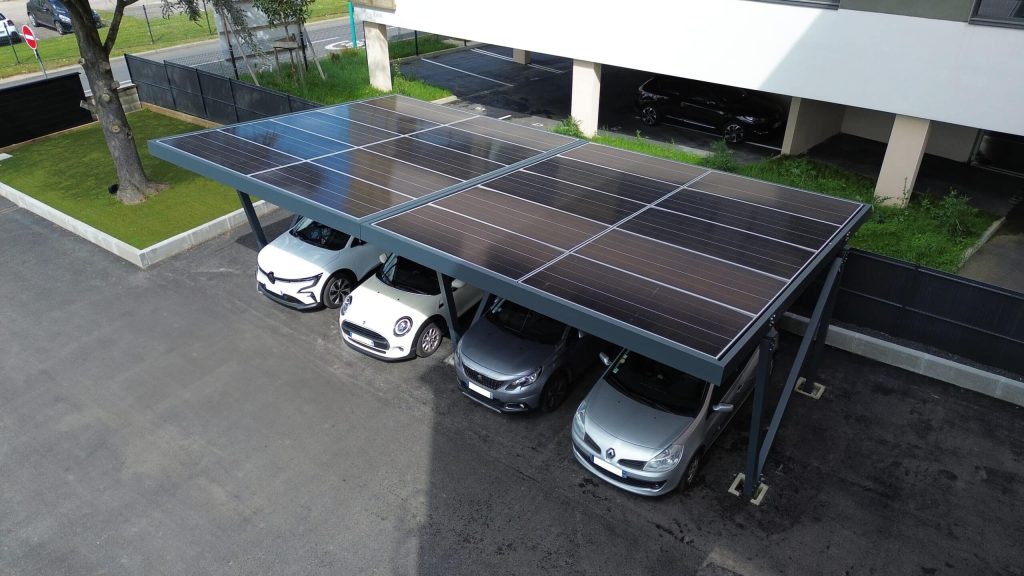 Un parking de résidence couvert de panneaux solaires Vue aérienne d'un carport solaire couvrant quatre voitures sur le parking d'une résidence