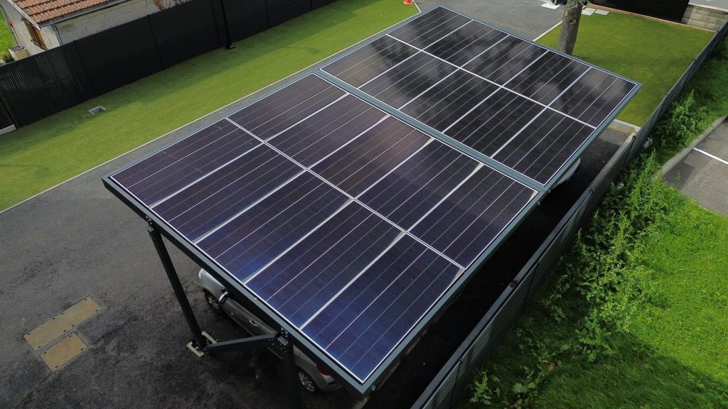 Un toit de carport qui produit de l'électricité Vue plongeante sur les panneaux photovoltaïques du toit d'un carport solaire installé le long d'une pelouse