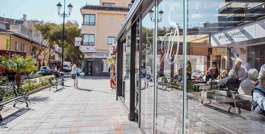 Une terrasse fermée sans perdre la vue Terrasse de restaurant fermée par des rideaux de verre, vue depuis une place piétonne ensoleillée